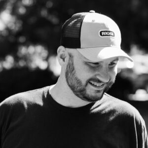 Black and white portrait of a smiling man wearing a cap, representing Wapiti Digital's friendly and professional team.