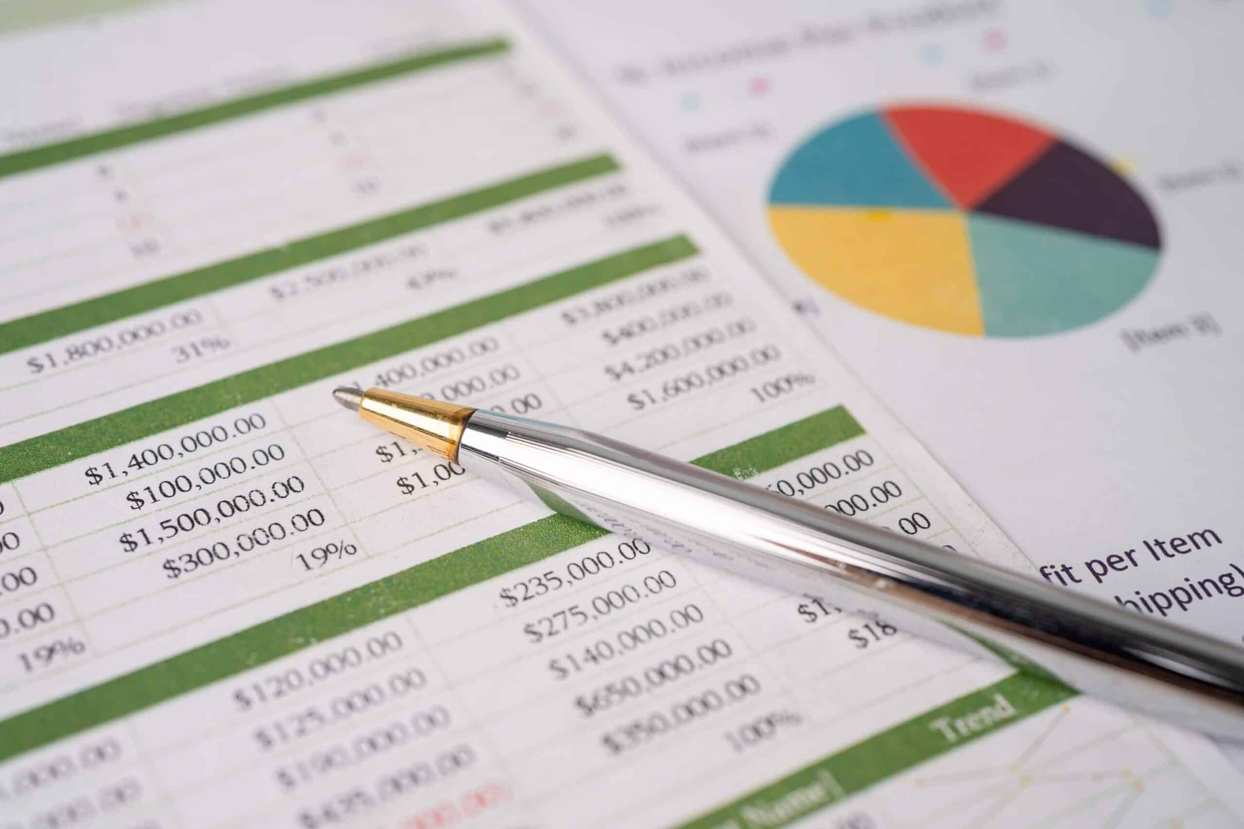 Close-up of financial spreadsheets with a pen and colorful pie chart for data analysis and business insights.