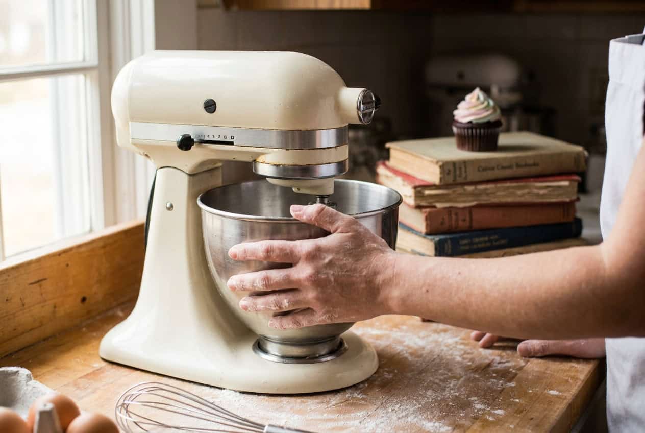 Why We Build With Developer-Focused Page Builders (and Skip the Rest) 1 Baker steadying a stand mixer bowl in a small bakery kitchen, a cupcake resting on a stack of worn cookbooks